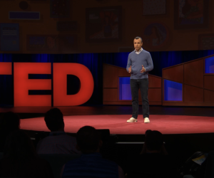 Guy Winch standing on a stage giving a TED Talk on how to fix a broken heart